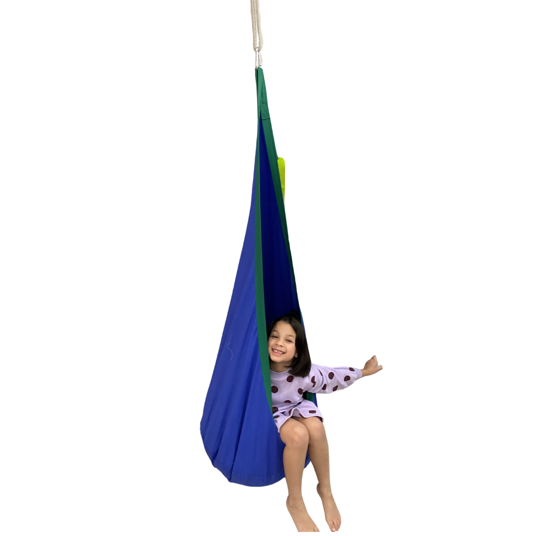 Child in a blue and green hanging pod swing on a white background