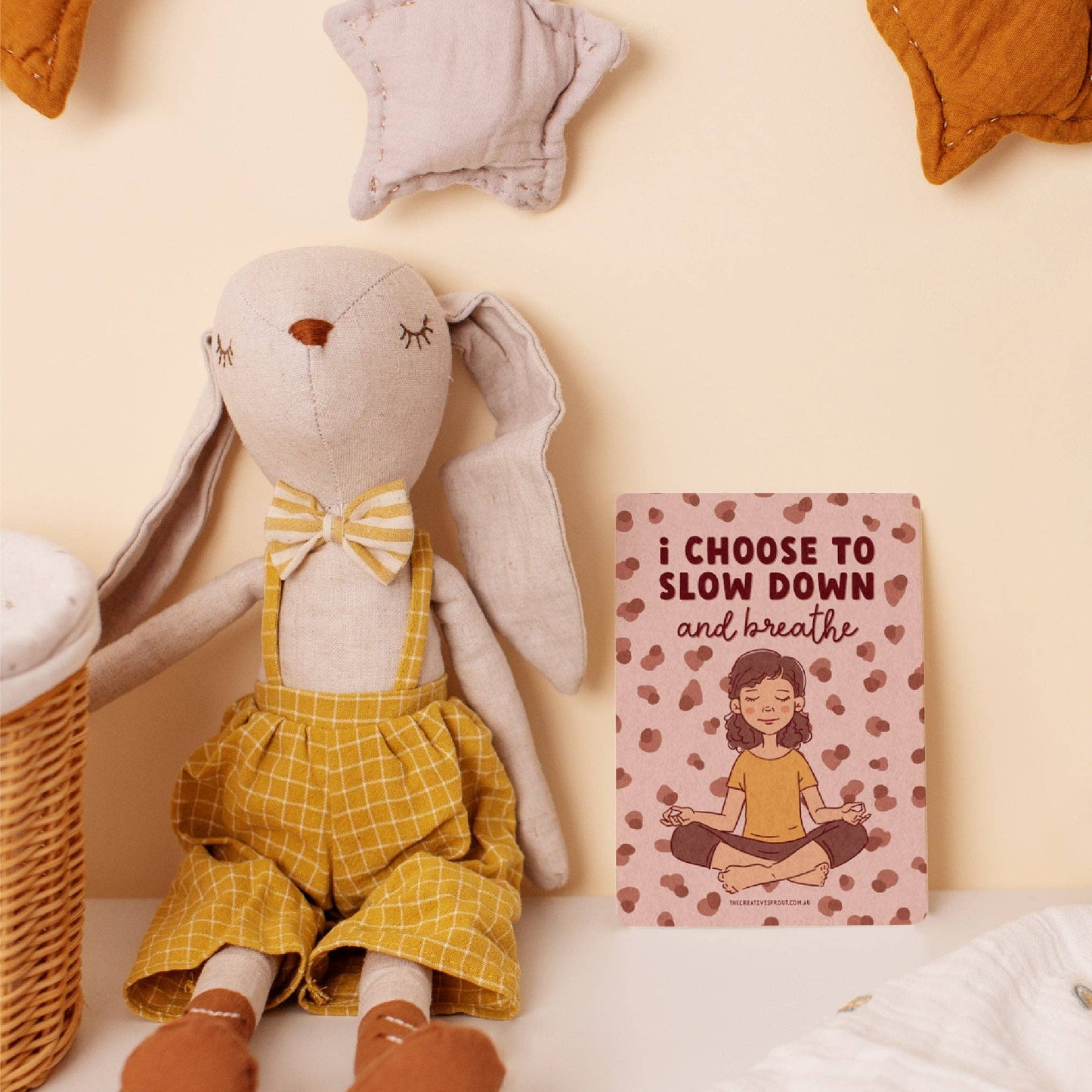 Stuffed rabbit toy in a yellow outfit next to an anxiety affirmation card for kids promoting mindfulness to slow down and breath
