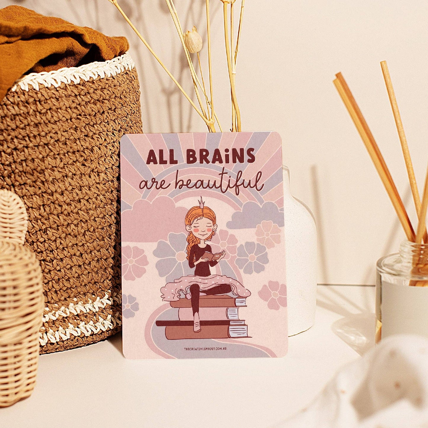 Kids Affirmation card 'All Brains are Beautiful' against a basket and diffuser