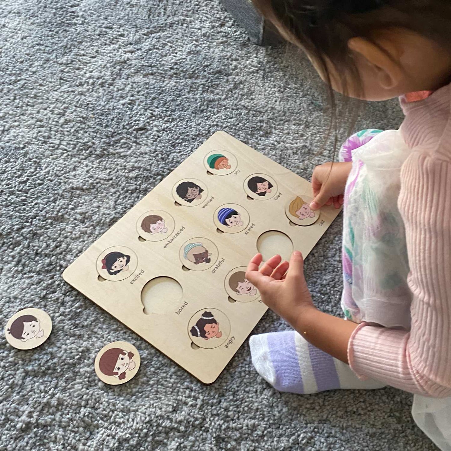 child completing wooden feeling puzzle