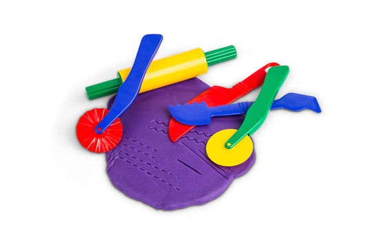 Set of five colourful fun dough toys accessories laying on flattened purple play dough.