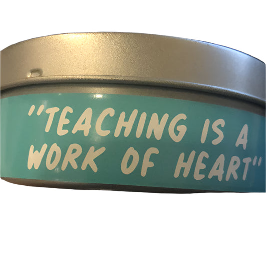 Metallic container with 'Teaching is a work of heart' text on a teal background