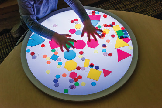 Child playing with translucent shapes on the round light panel