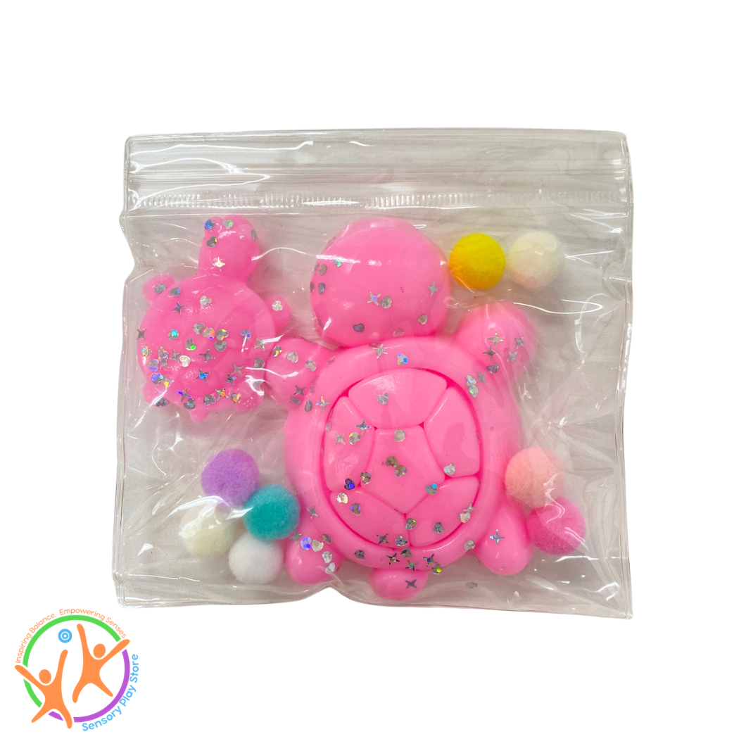 Pink sticky turtle fidget toy with colourful pom-poms in a clear plastic bag on a white background