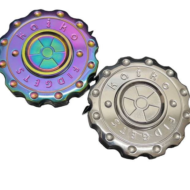 Two haptic dual function Kaiko fidget spinners, one colourful and one silver, on a textured black surface.