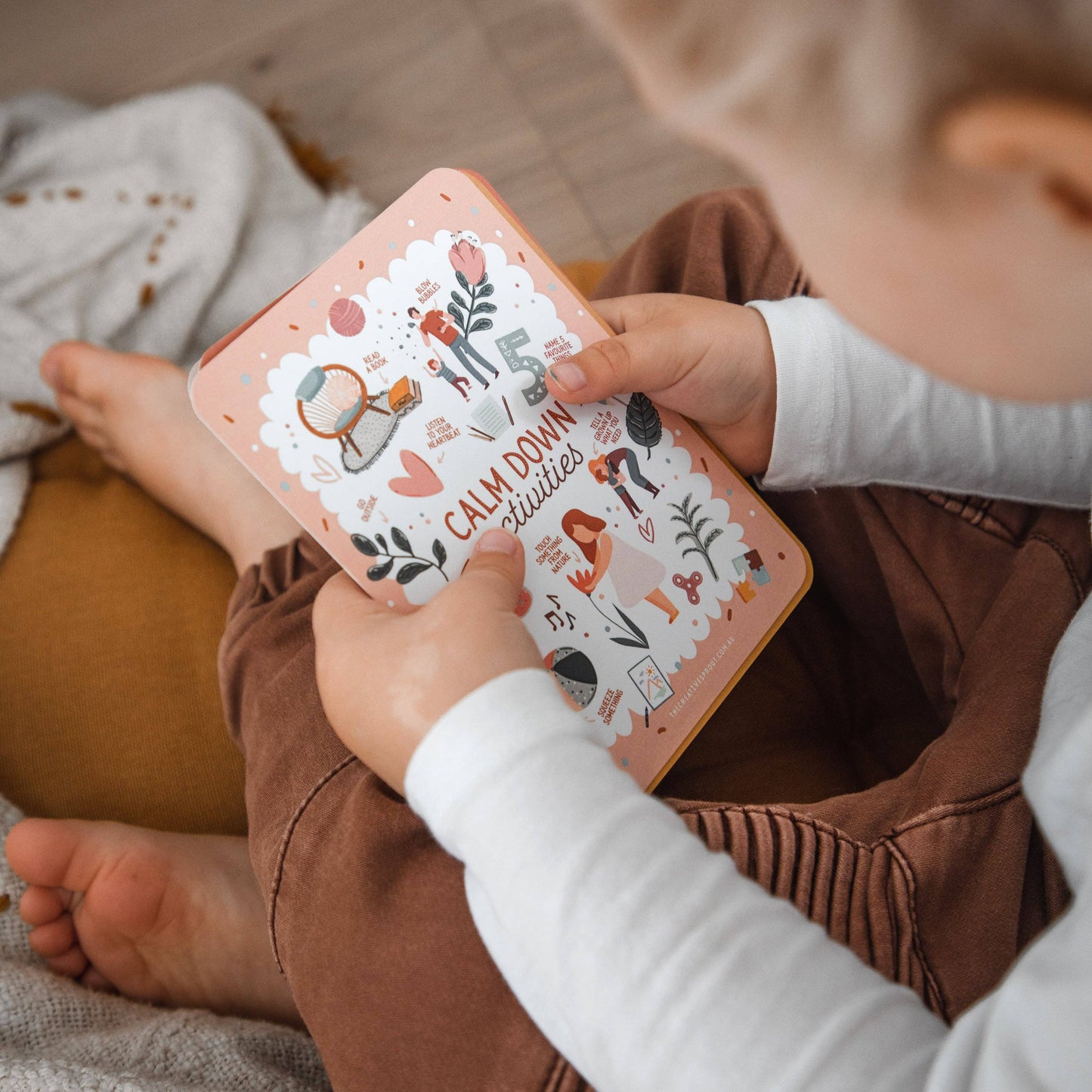 Child holding a a stack of cards 'Calm Down Activities'