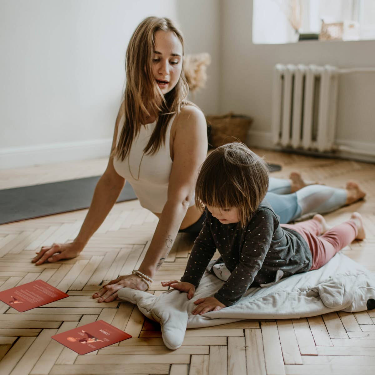 Woman and child doing yoga pose on floor with flash cards