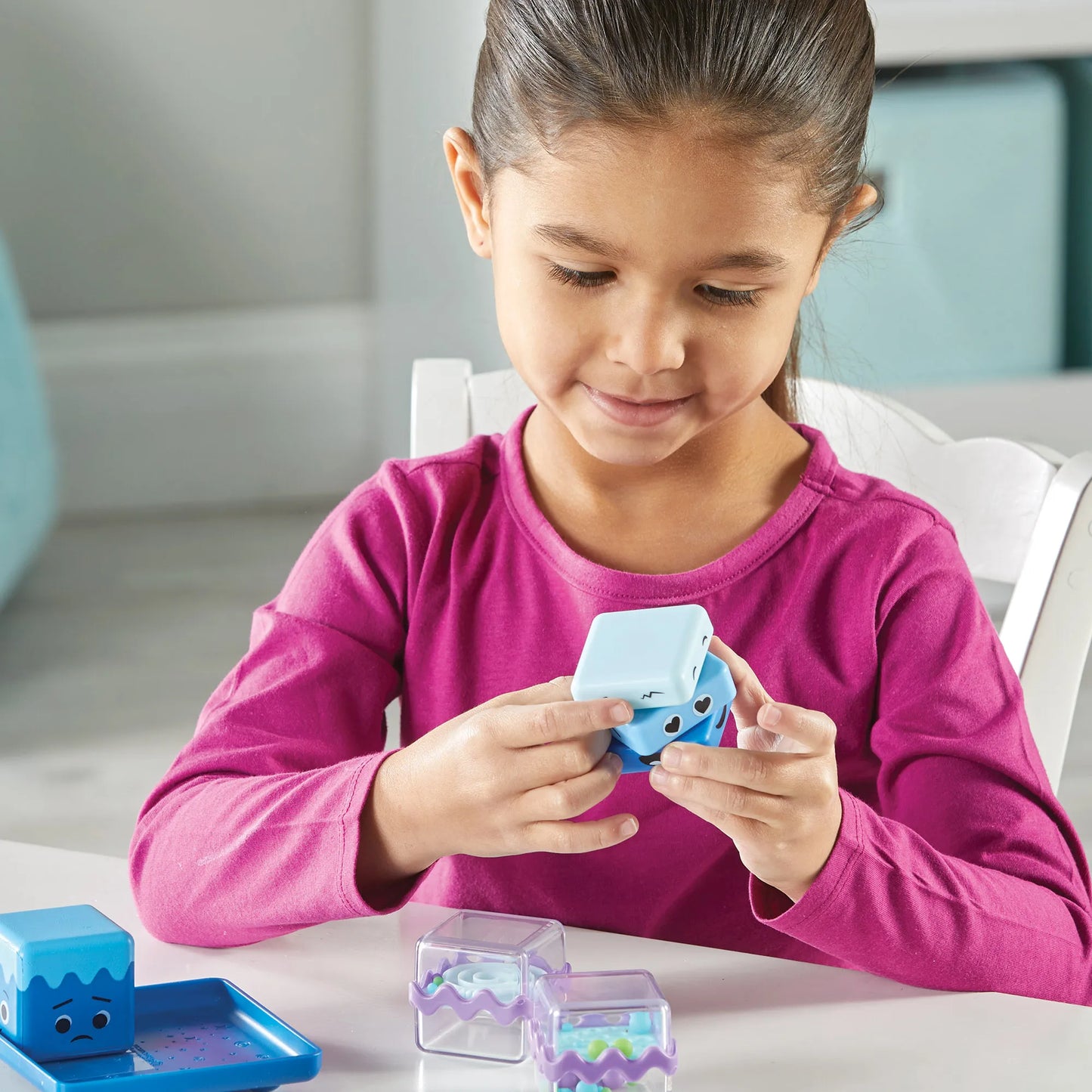 Young girl twisting the cool down fidget cube with other sensory fidget cubes on the table