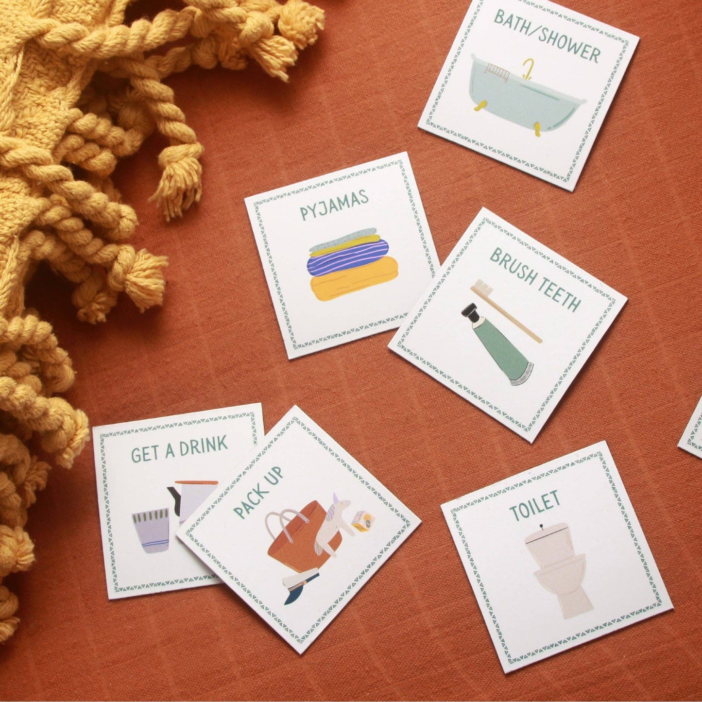 Educational cards with illustrations and text on a wooden surface with a yellow textured fabric.