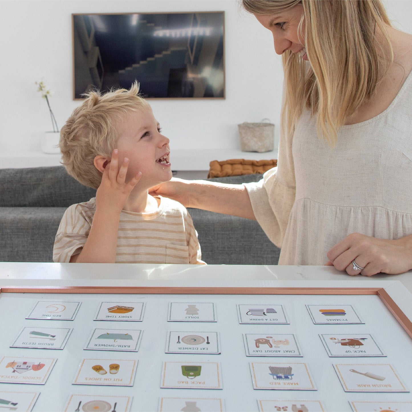 Woman and child interacting with visual schedule cards on a tmagnetic board