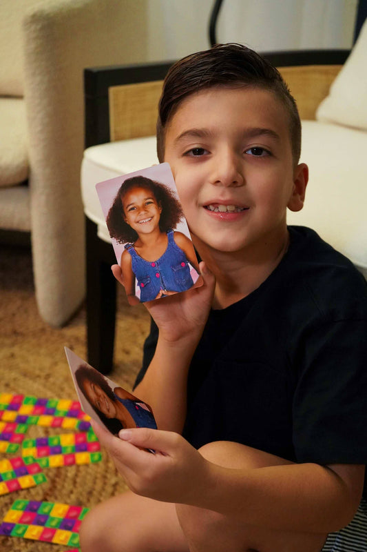 Child holding a card with a picture of a girl smiling.