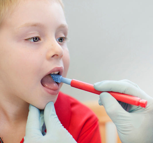 Ark Z Vibe with probe tip inside the side of a girls mouth with an adult wearing gloves assisting