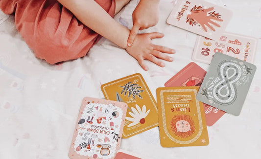 A child and The Creative Sprout Calm Down Cards on a bed