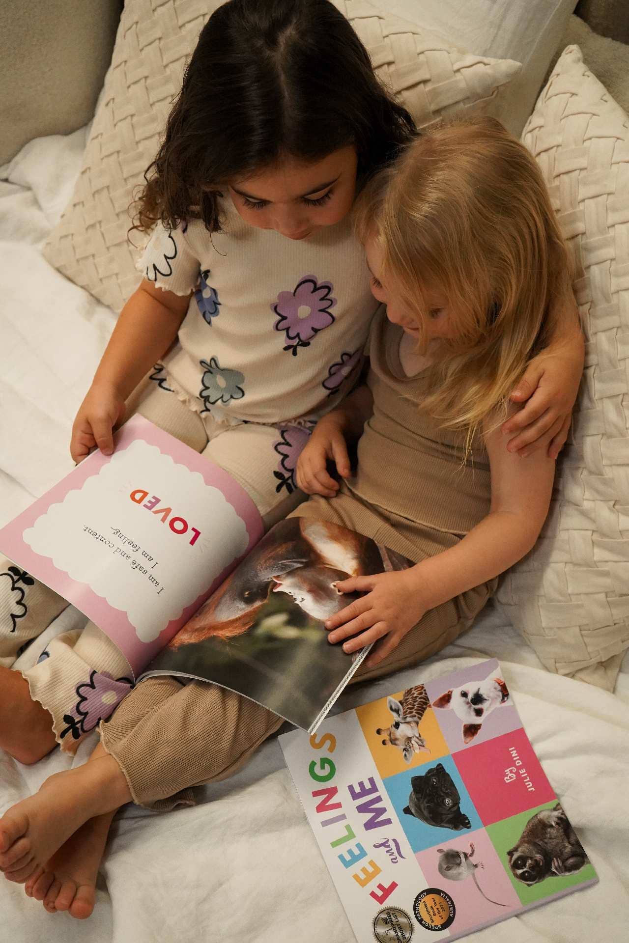 Two children reading a book together on a bed