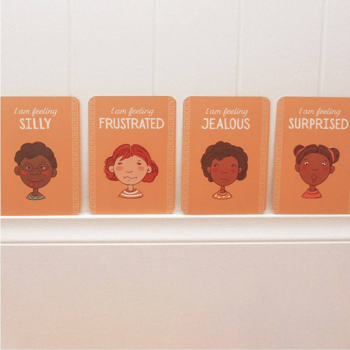 Four emotions cards in the yellow zone with illustrations of children's faces and emotions on a white shelf.
