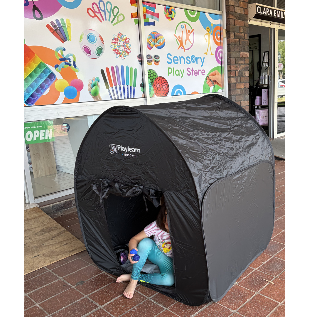Child playing inside a black sensory play tent outside Sensory Play Store