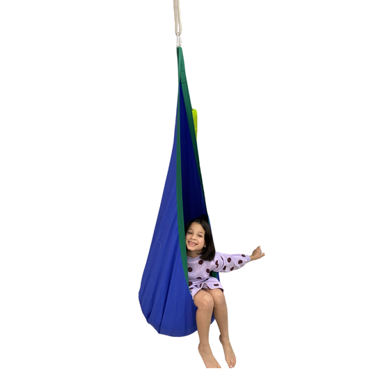 Child in a blue and green hanging pod swing on a white background