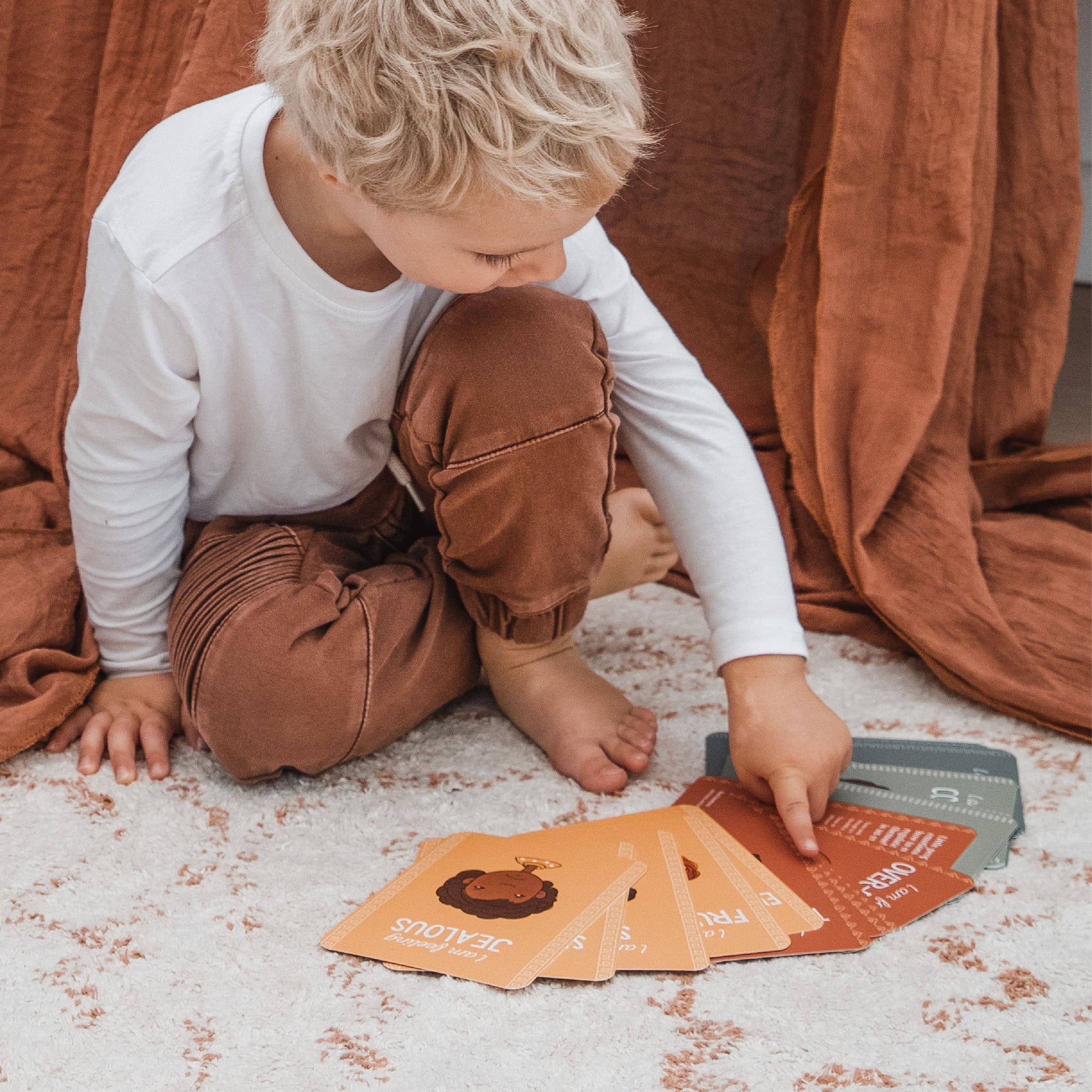 Child playing with educational emotions cards on a carpeted floor