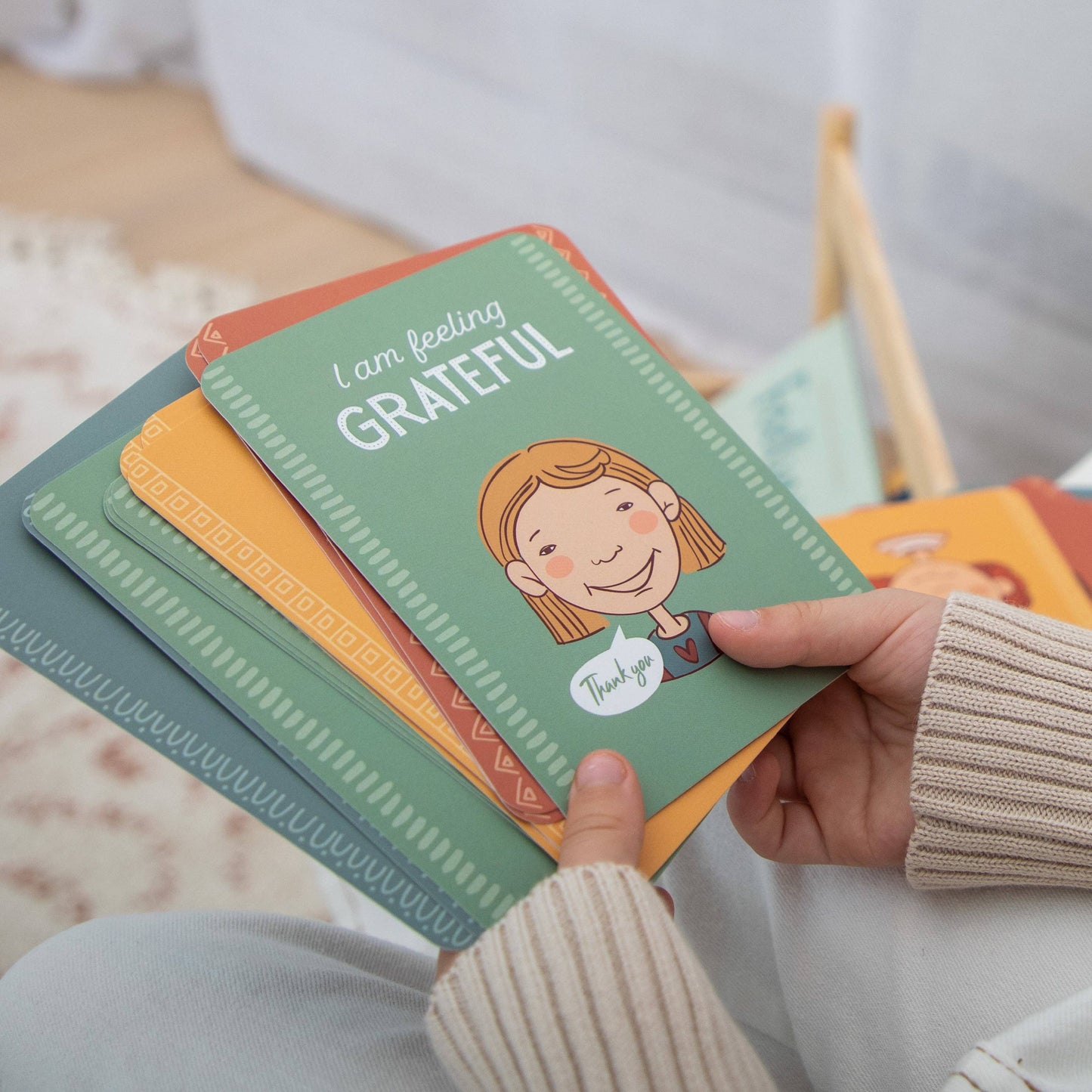 child holding a stack of colorful emotional regulation flash cards 