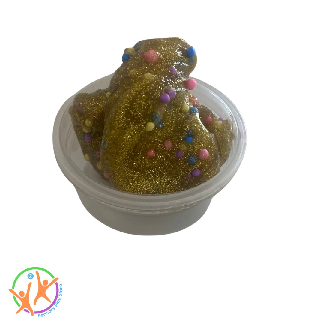 Gold glittery slime or putty with colourful beads in a clear container on a white background