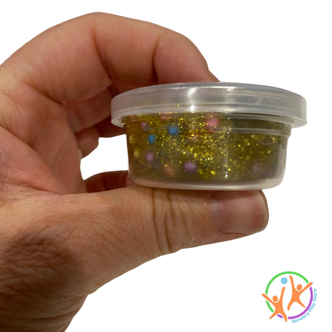 Hand holding a small container of gold glitter putty buy sensory play store