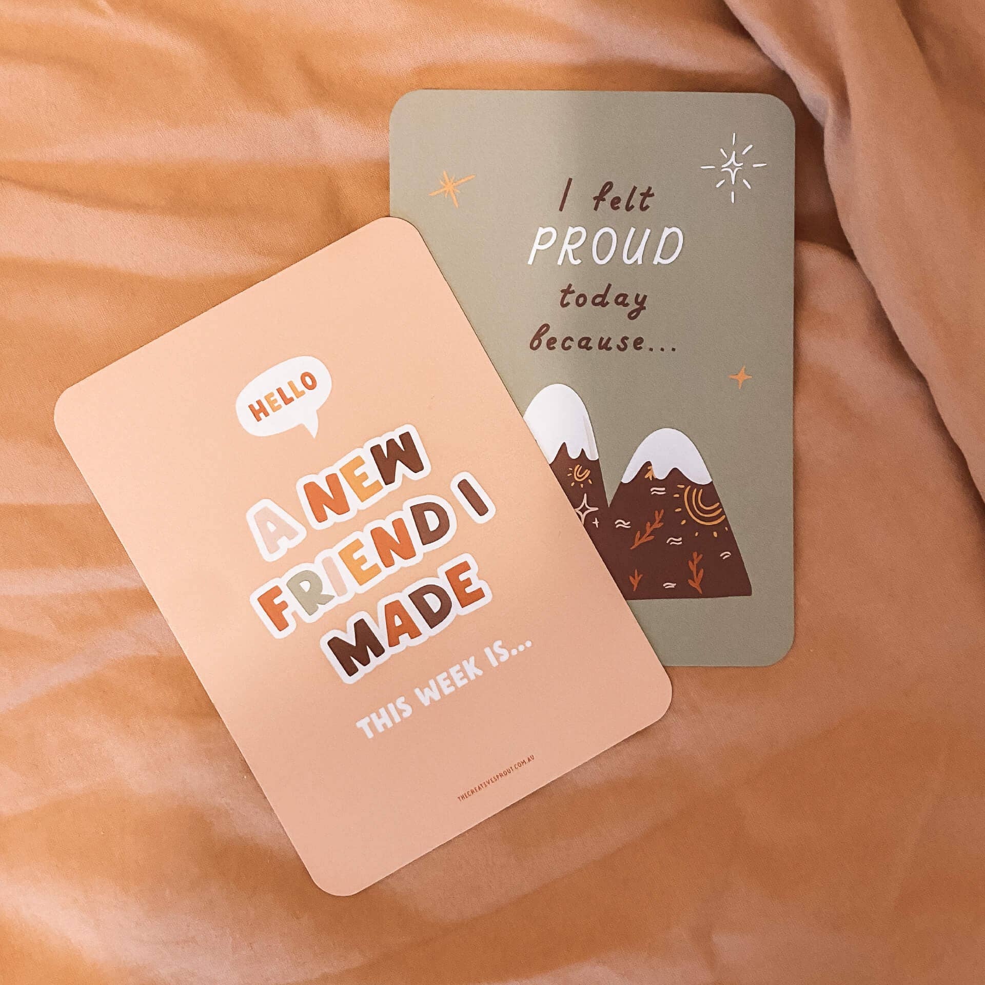 Two gratitude cards on a soft fabric background, one with text and the other with mountain illustration.