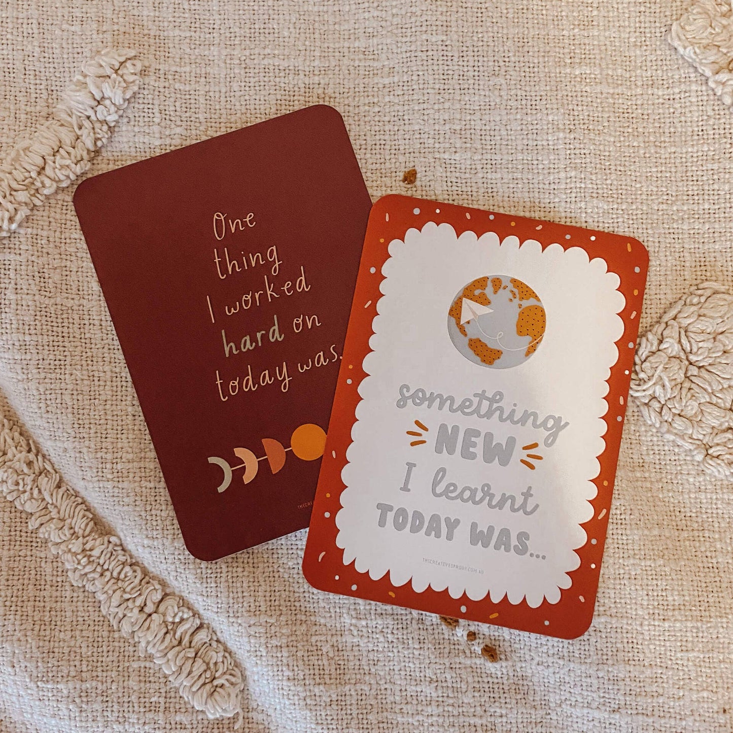 Two cards with motivational phrases on a textured fabric background
