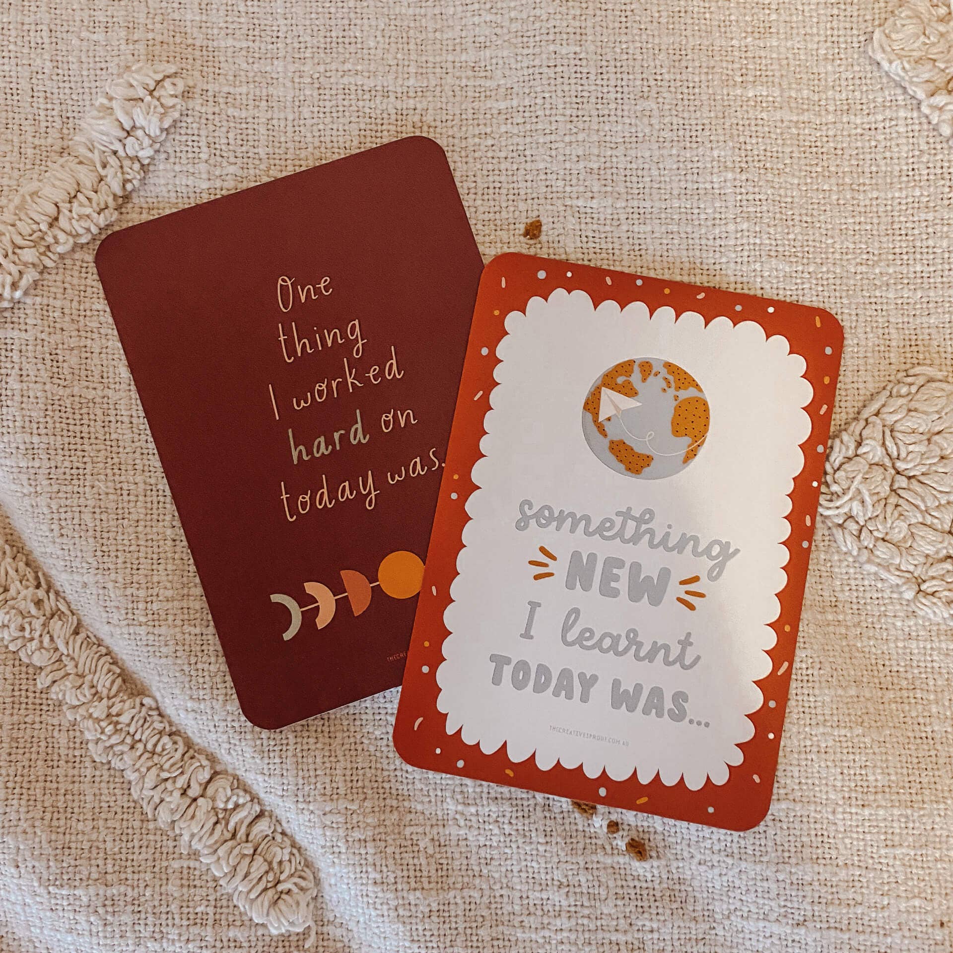 Two cards with motivational phrases on a textured fabric background