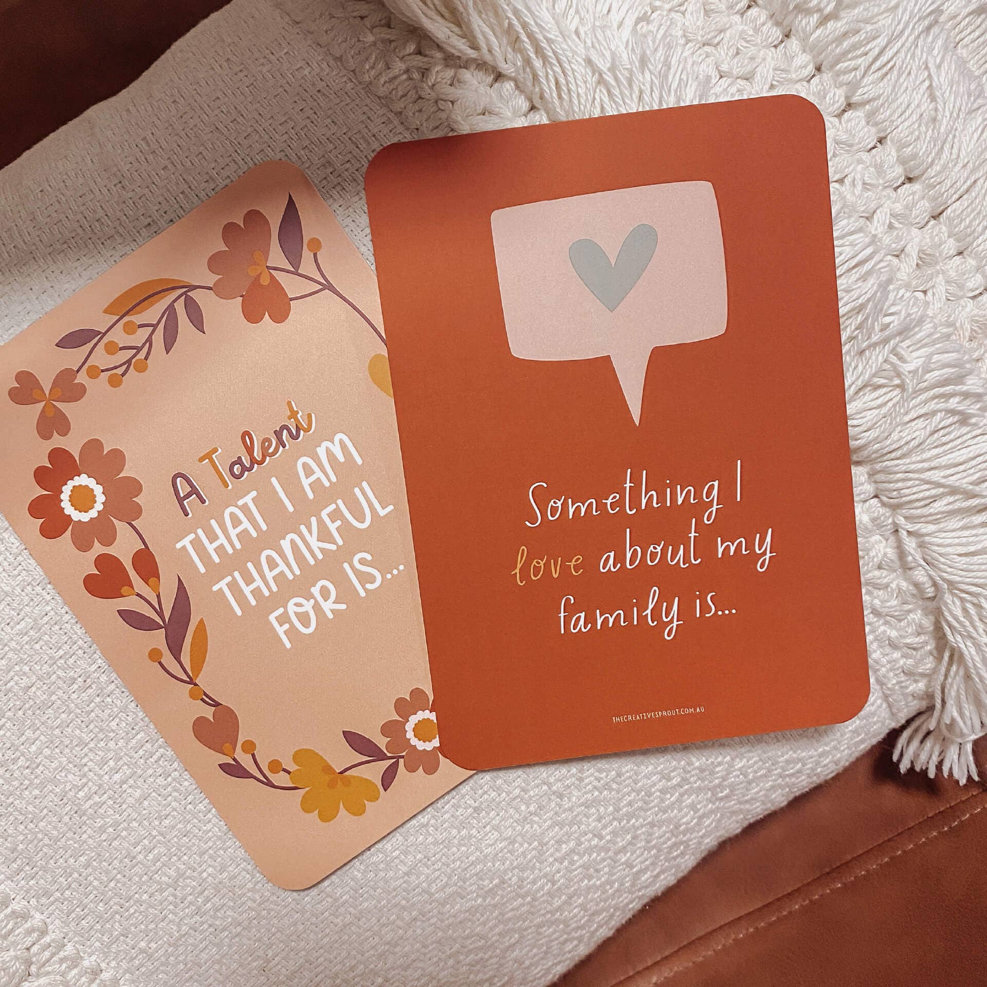 Two gratitude cards on a textured surface with floral and text designs.