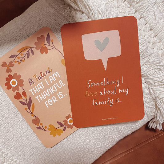 Two gratitude cards on a textured surface with floral and text designs.