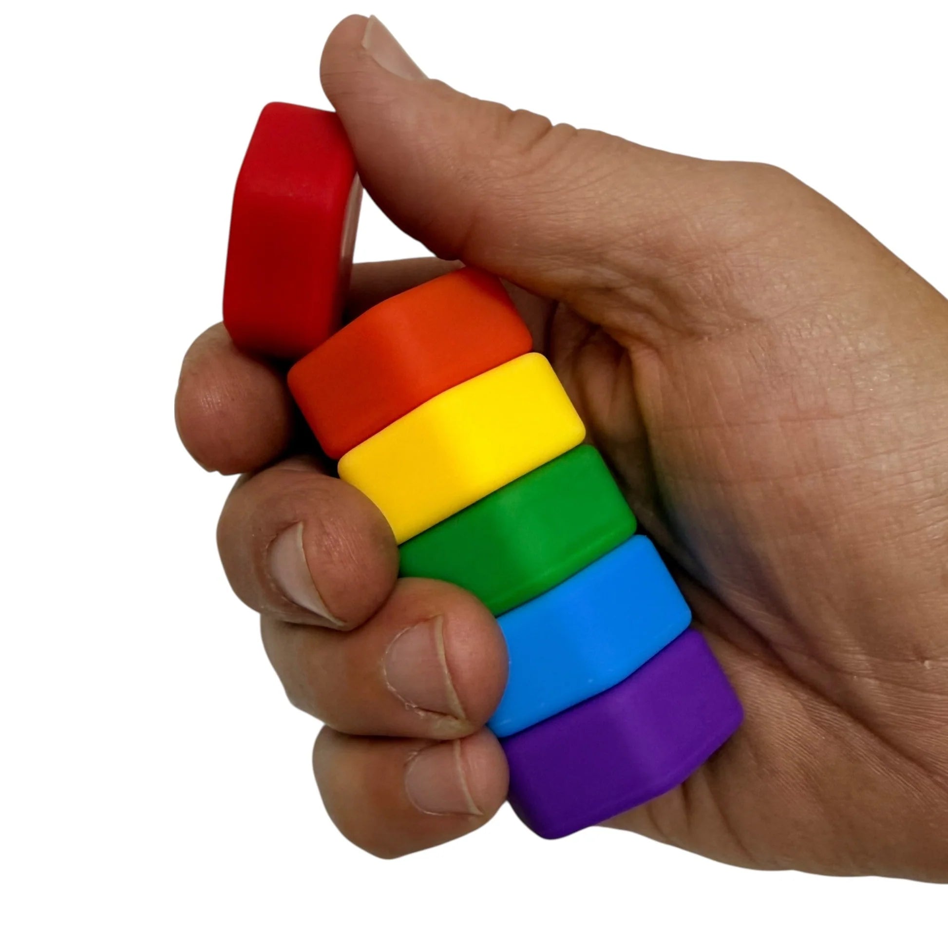 Hand holding MagStack rainbow silicone covered magnets against a white background