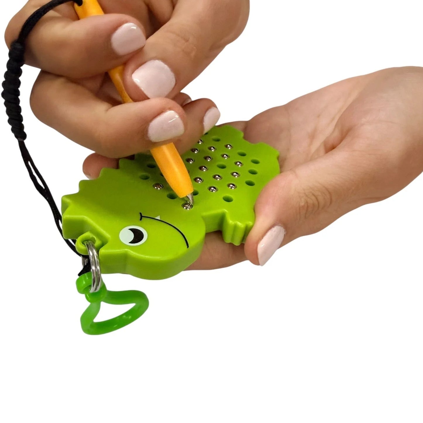 Hand using Kaiko dinosaur shaped magnetic pad keyring on a white background