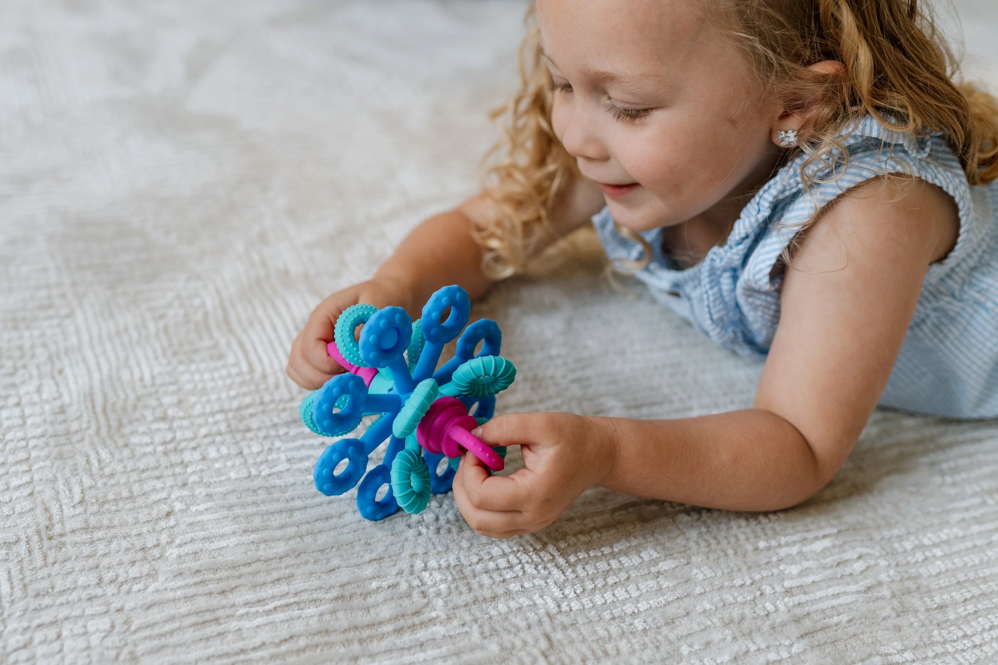 Child playing with a colorful sensory activity toy on a textured surface