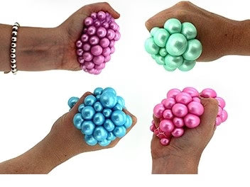Four hands holding different colored stress balls against a white background