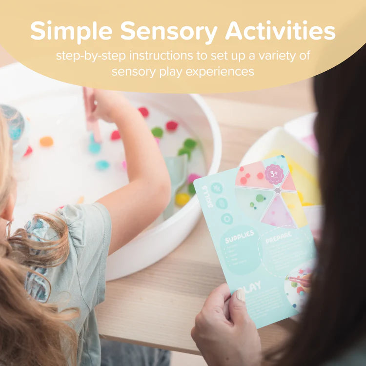 Woman holding a card with sensory play activities for a child playing with a sensory play tray