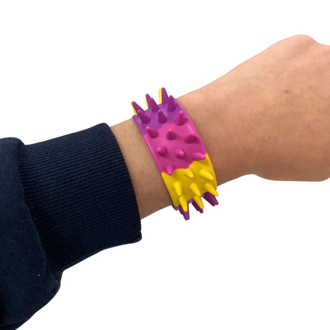 Colourful spiked wristband on a wrist with a white background