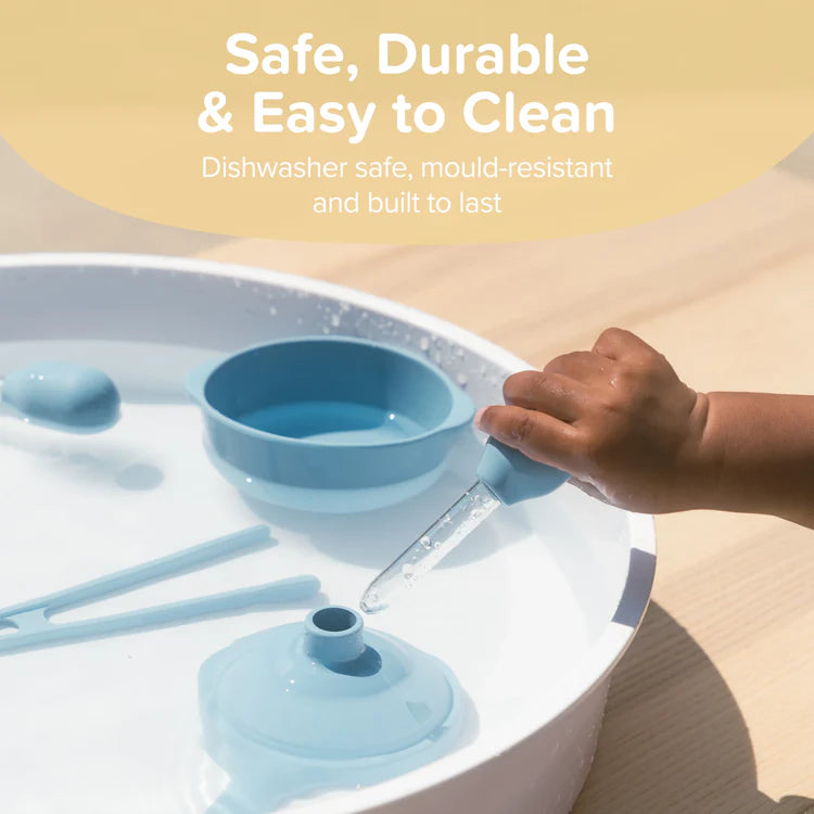 little hand holding a dropper over the water play tray with the starter kit