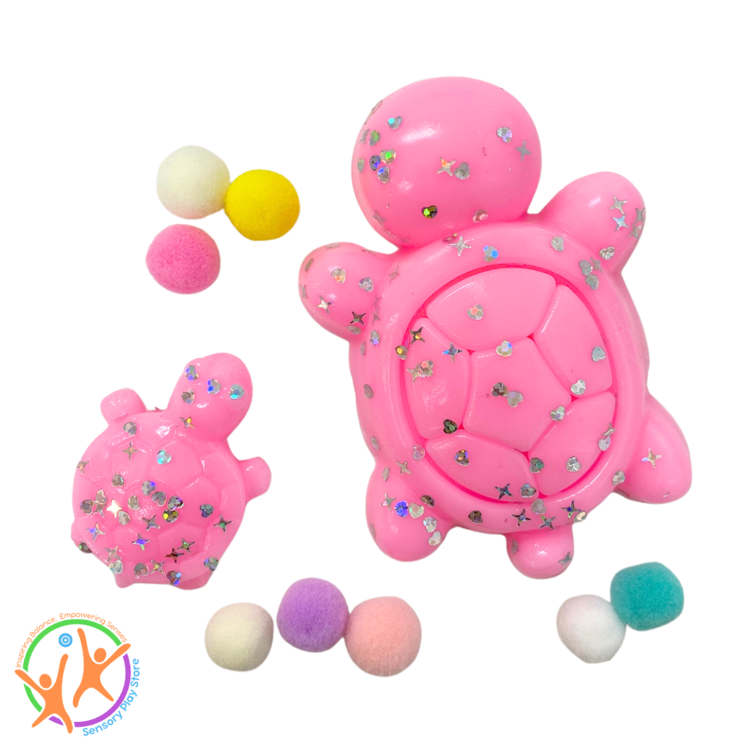 Pink sticky turtle fidget toy with colorful pom-poms on a white background
