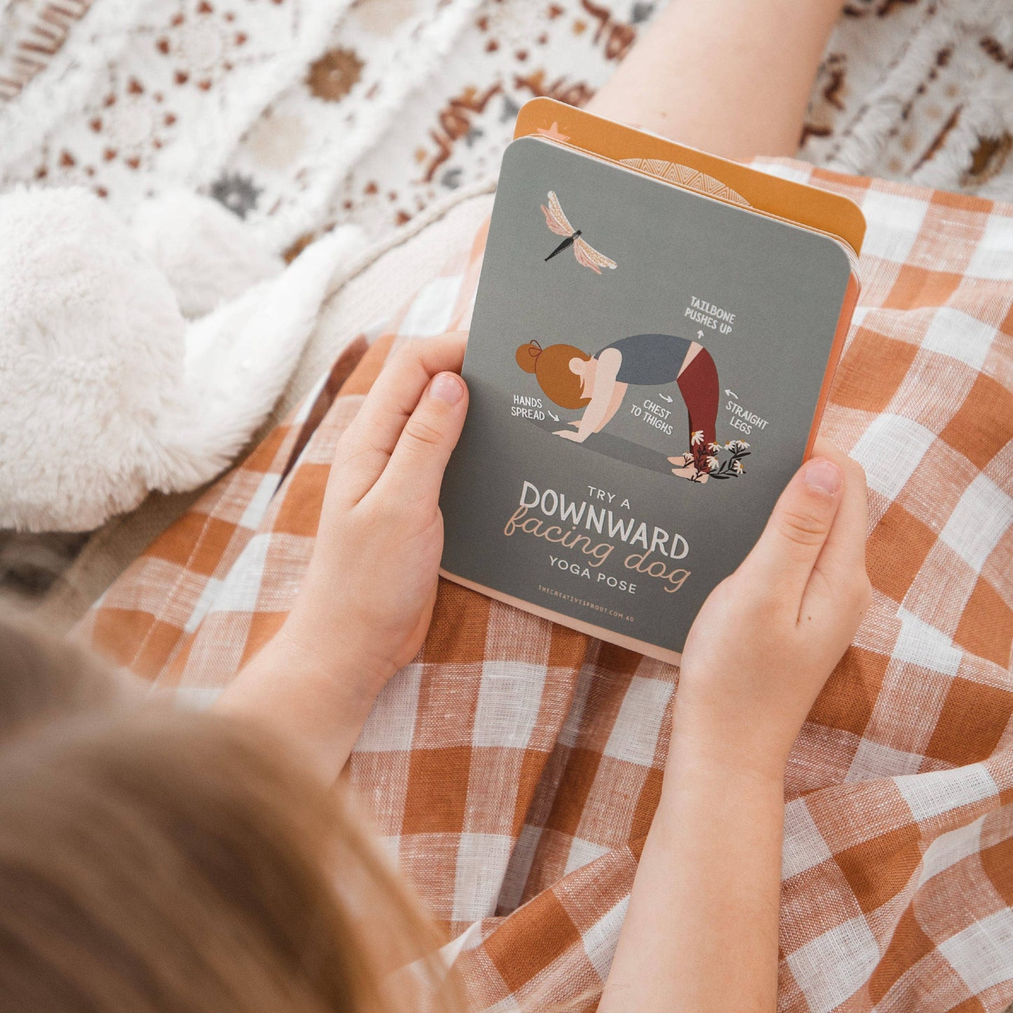 Person holding a yoga pose card on a checkered blanket