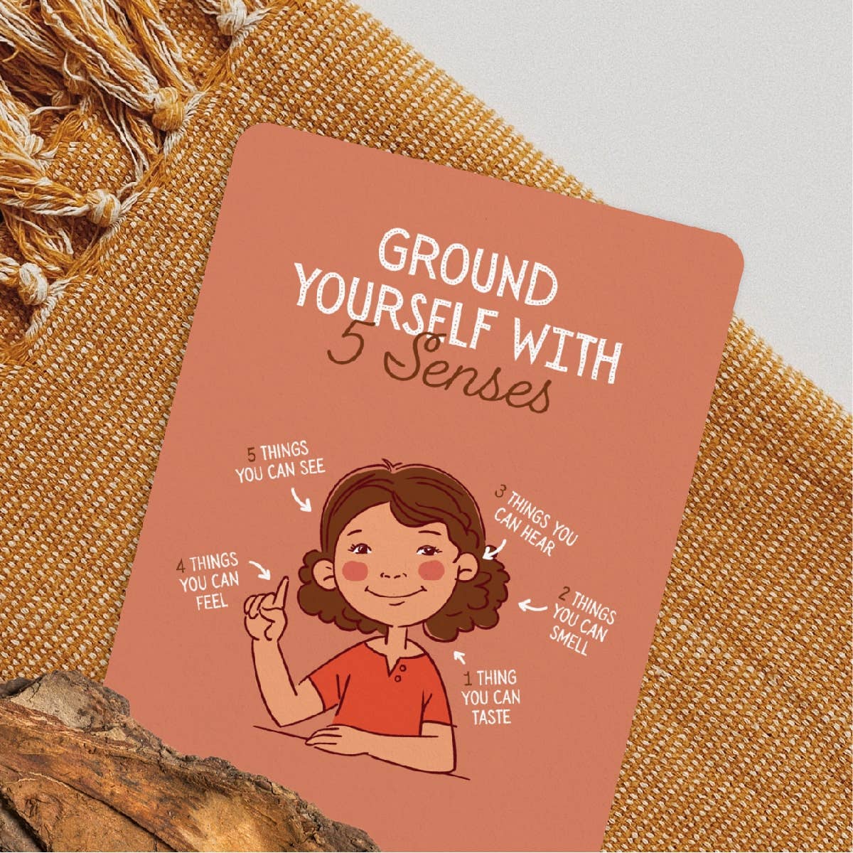 Card with 'Ground Yourself with 5 Senses' text and illustrations on a textured surface.