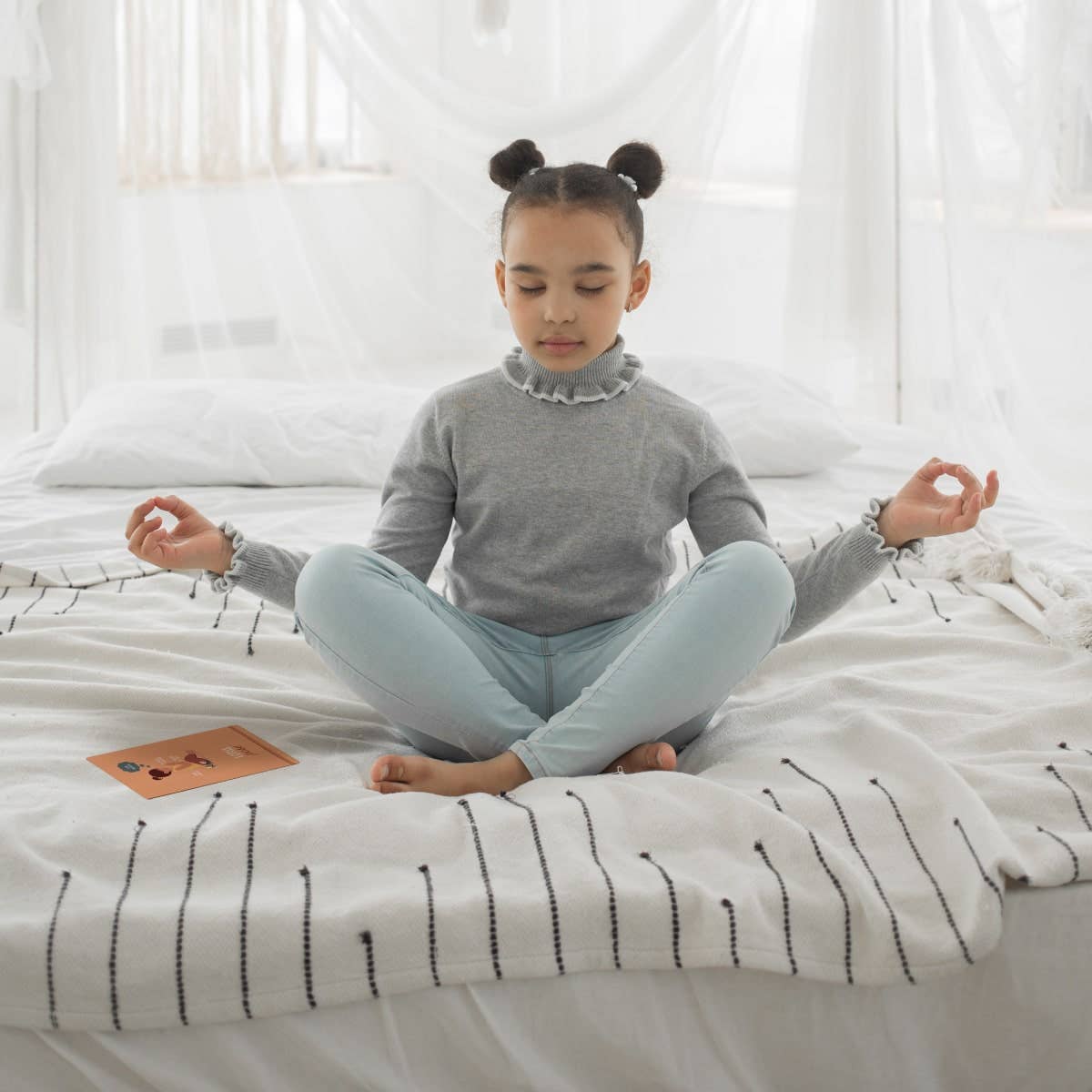 Young girl meditating on a bed in a bright room