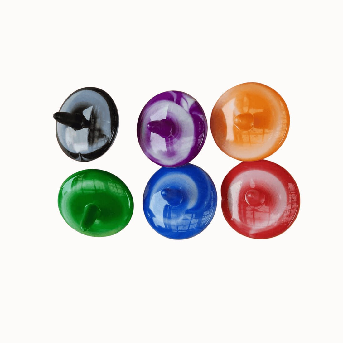 Six assorted tie-dye spinning tops in black, purple, orange, green, blue, and red, arranged in two rows against a white background. Each plastic top features a swirling, marbled pattern.