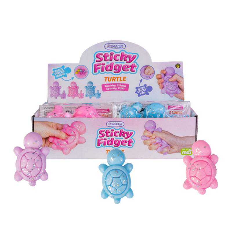 Three colorful Sticky Fidget Turtles in pastel pink, blue, and purple with glitter shells, shown in a retail display box.