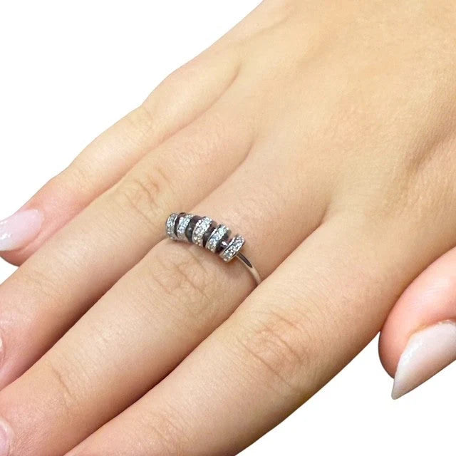 Silver Axia Fidget ring with 5 small diamante beads on a finger against a white background