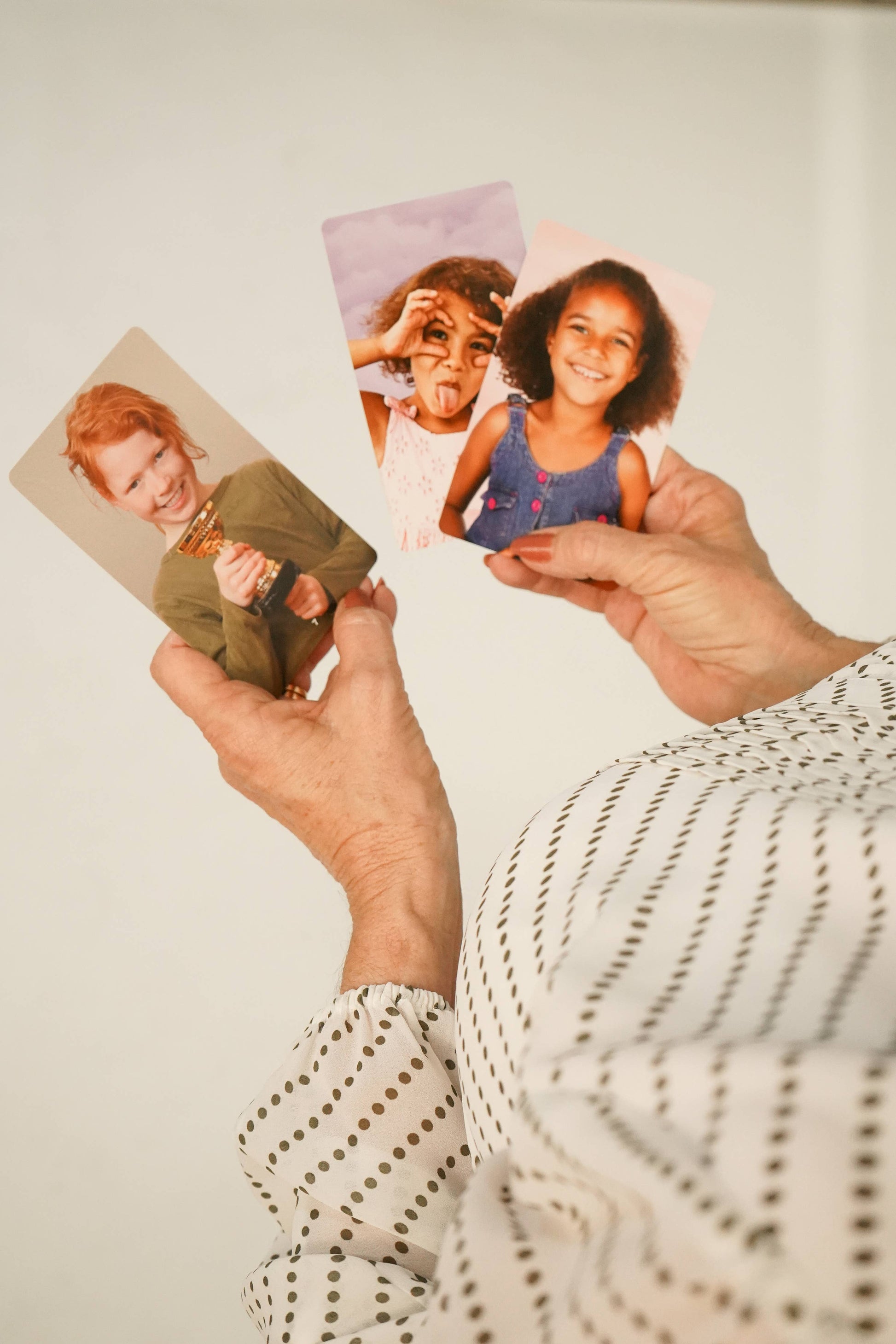 Person holding emotion cards with photos of children against a plain background