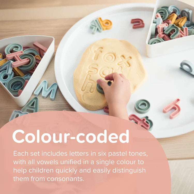 Childs hand using the silicone letters to stamp playdough on a sensory play tray lid
