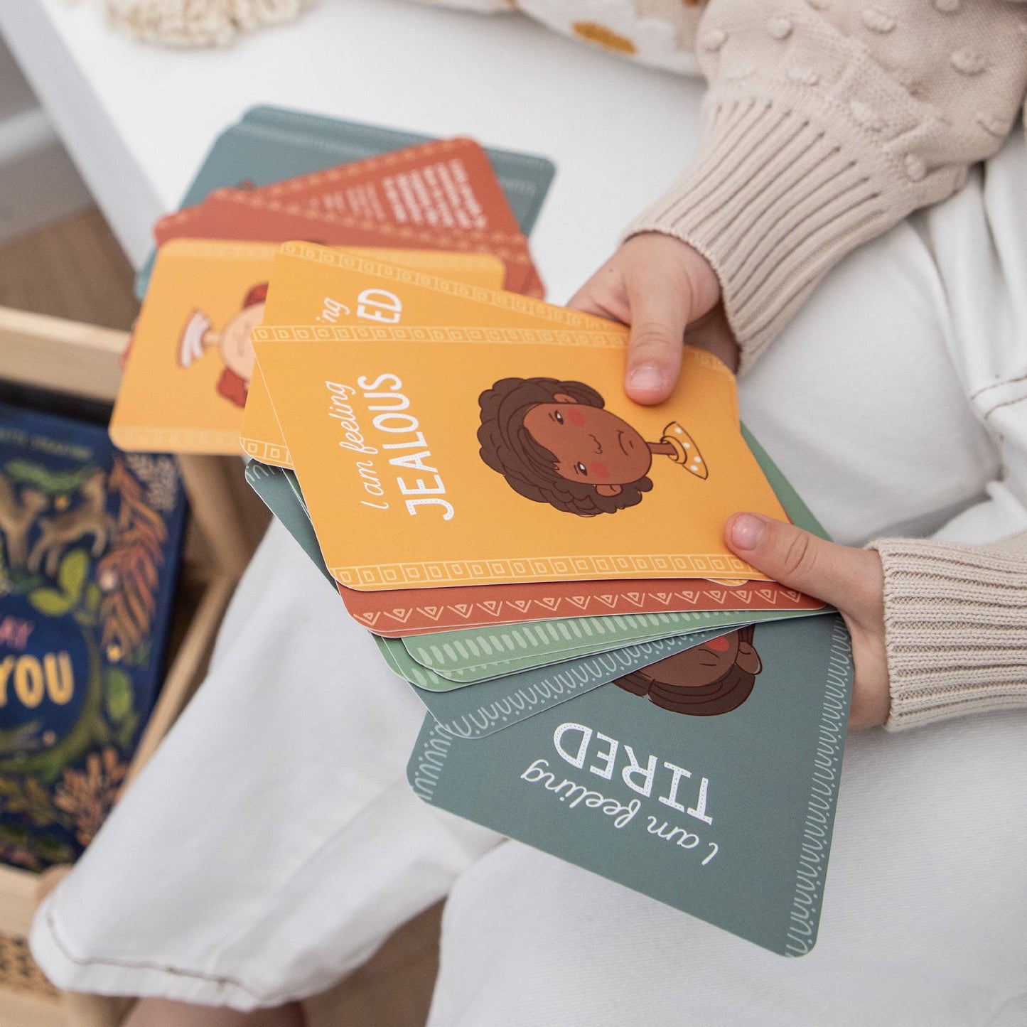 child's Hand holding a stack of creative sprout emotions cards for kids with illustrations and text.