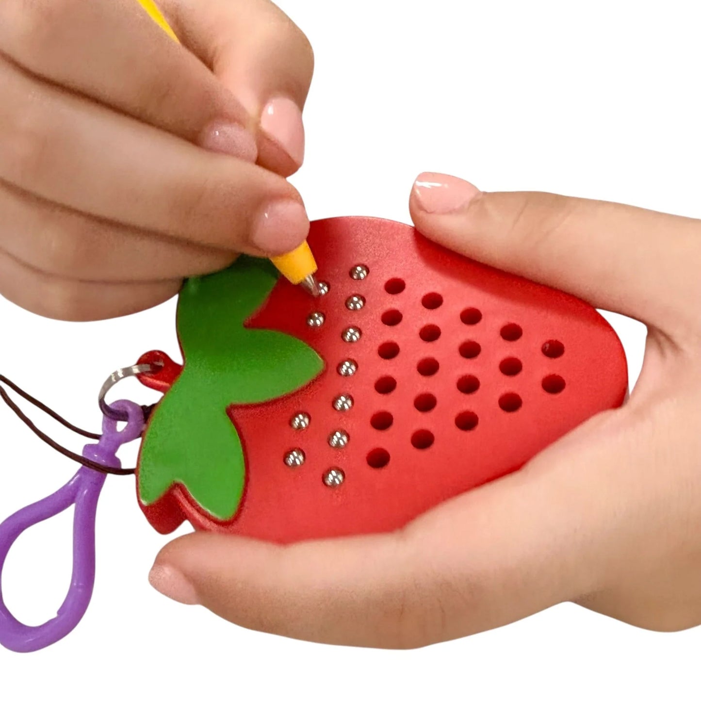 Kaiko strawberry magnetic pad keyring being held by a hand on a white background