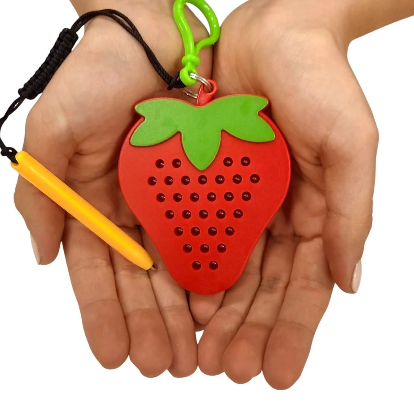 Kaiko strawberry magnetic pad keyring being held by a hand on a white background