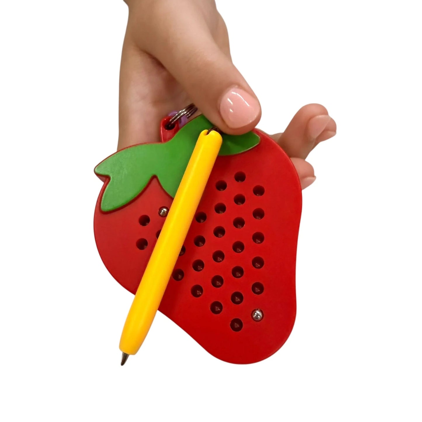 Kaiko strawberry magnetic pad keyring being held by a hand on a white background